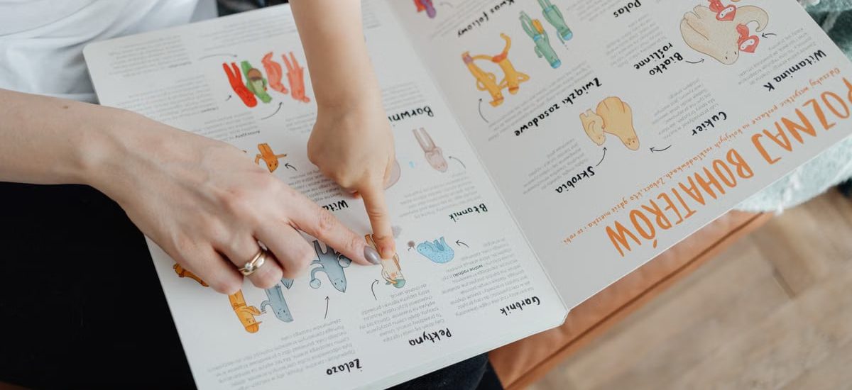 A child and adult engaging with an educational book, pointing to illustrations.